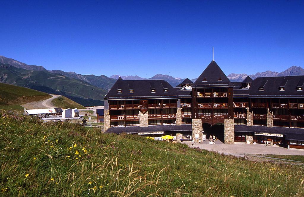 a large building on a hill with mountains in the background at Résidence Vacancéole - Privilège in Germ