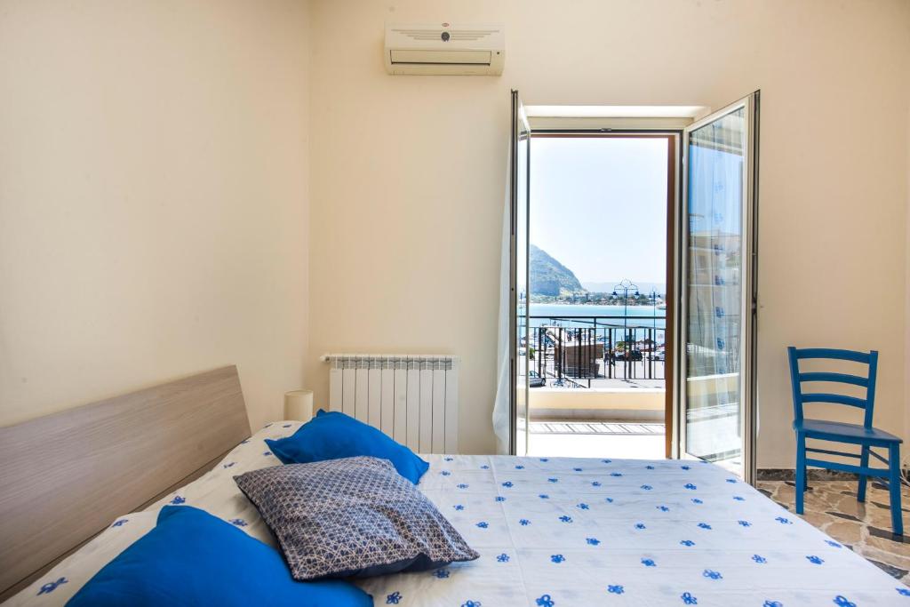 sypialnia z łóżkiem z niebieskimi poduszkami i balkonem w obiekcie Casetta Vista Mare in Piazza a Mondello w mieście Palermo