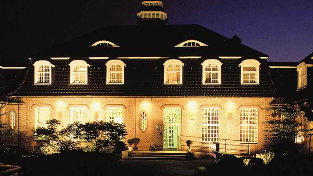 una grande casa illuminata di notte con luci di Hotel am Stadtpark a Hilden