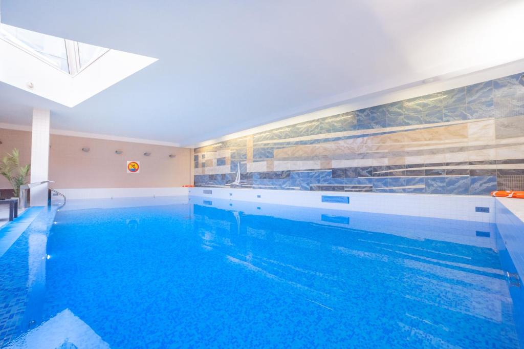 a large swimming pool with blue water in a room at Premier Kraków Hotel in Krakow