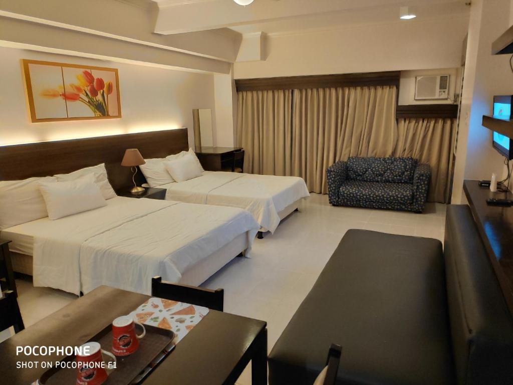 a hotel room with two beds and a chair at Tagaytay Staycation by Naya and Darla w Free Swimming Pool, WiFi & Netflix in Tagaytay