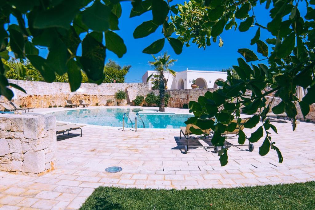 une piscine avec deux bancs et un arbre dans l'établissement Masseria Rosa Trulli Relais, à Alberobello