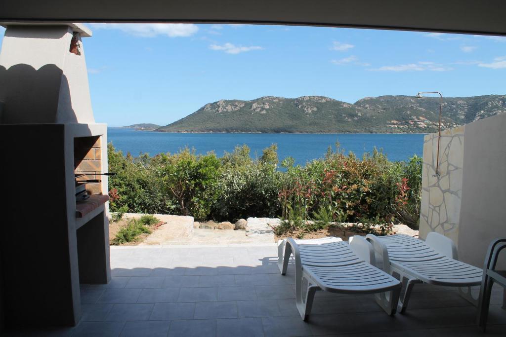 een patio met stoelen en uitzicht op het water bij Résidence Les Pavillons du Belvédère in Porto-Vecchio