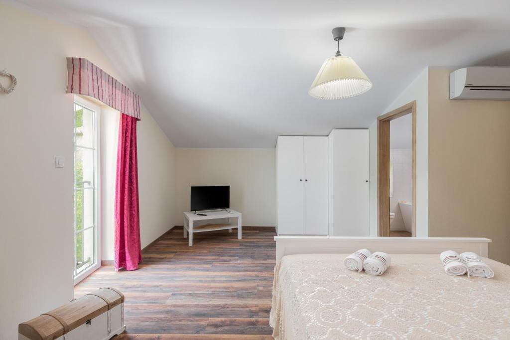 a white bedroom with a bed and a tv at Casa di nonno Giovanni in Buzet