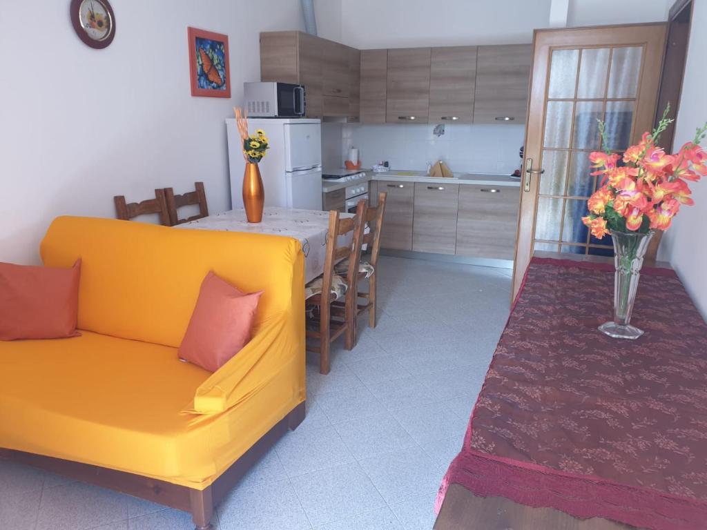 uma cozinha e sala de jantar com um sofá amarelo e uma mesa em Pretty Appartament Beb em Alghero