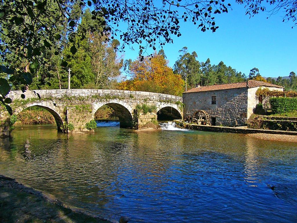 a stone bridge over a river next to a building at Moinho de Estoraos in Ponte de Lima