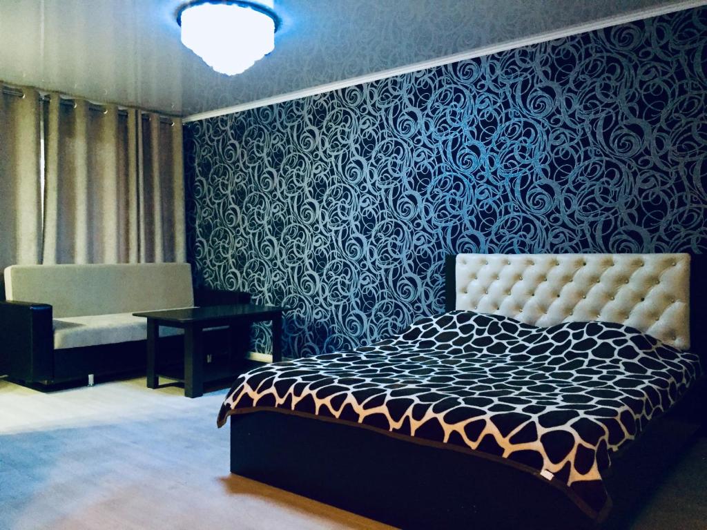 1 dormitorio con cama y pared azul en Димитрова 80/1 Апартаменты в Темиртау, en Temirtaū