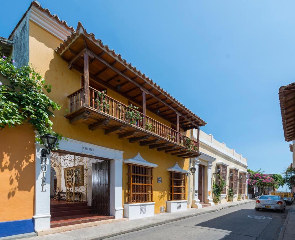un edificio amarillo con balcón en una calle en Casa Del Curato en Cartagena de Indias