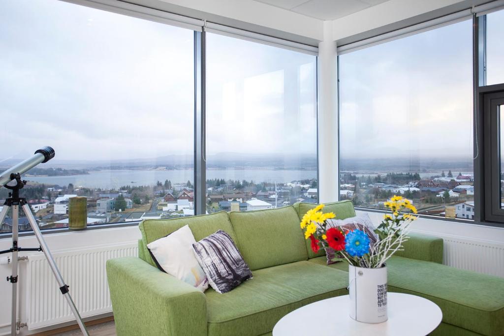 sala de estar con sofá verde y ventanas grandes en Blue Mountain Apartments by Heimaleiga, en Reikiavik