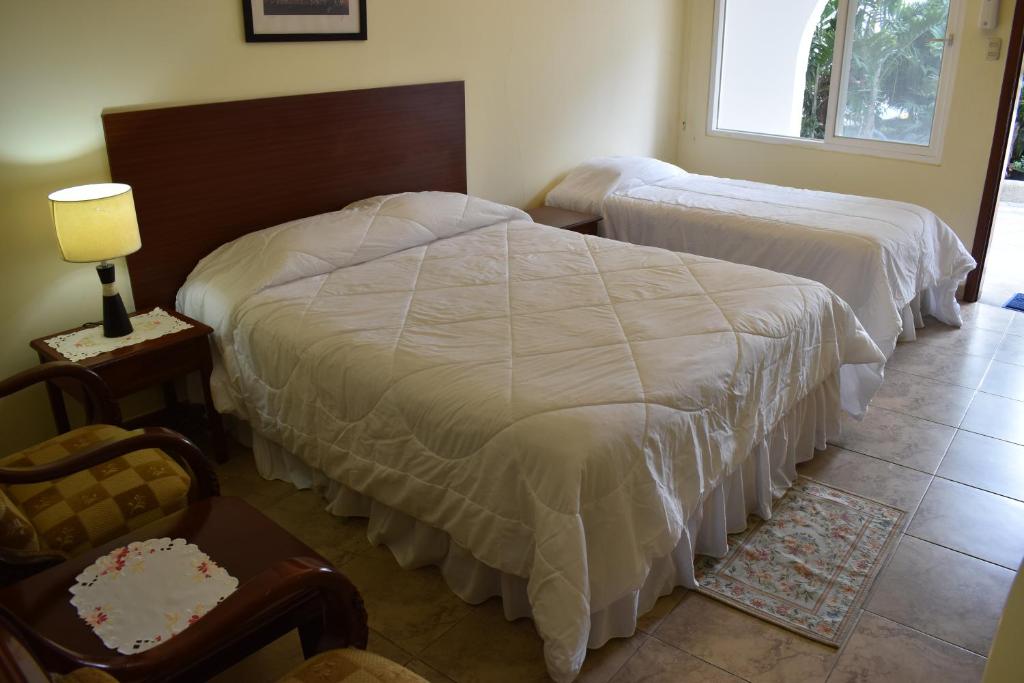 a bedroom with two beds and a lamp and a chair at Hosteria Palmetto in Playas