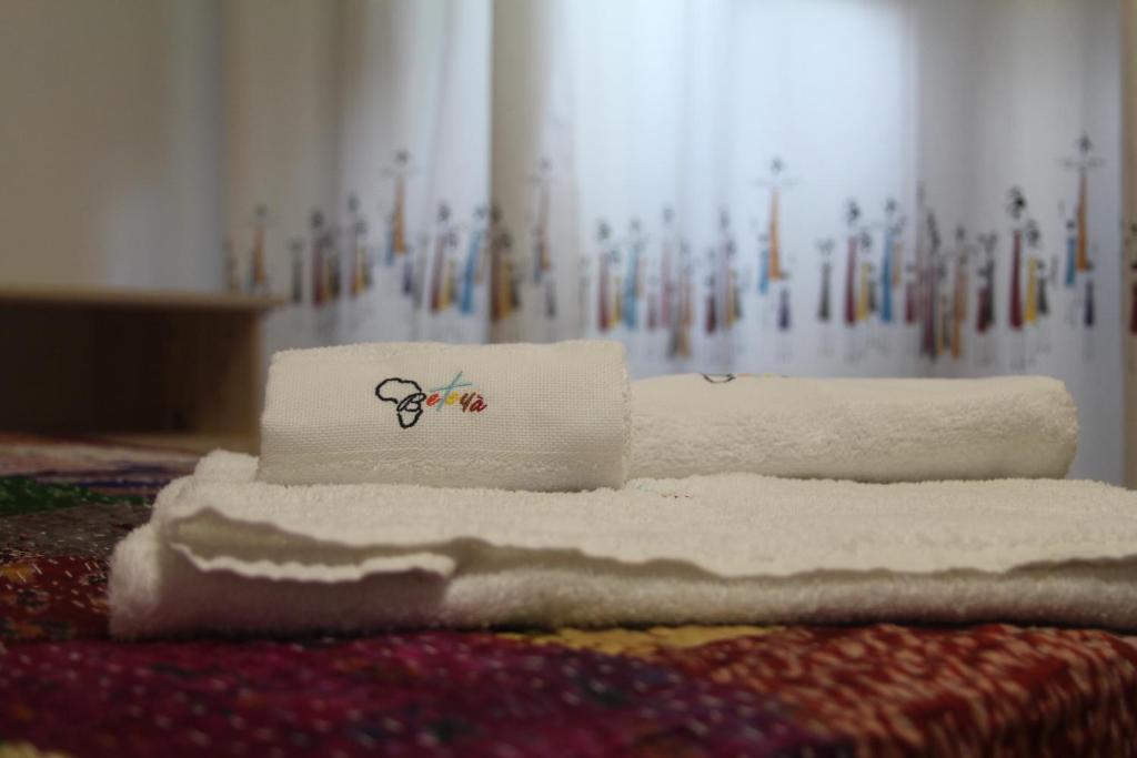 een stapel handdoeken bovenop een bed bij Beteyà Hostel Don Bosco in Catania