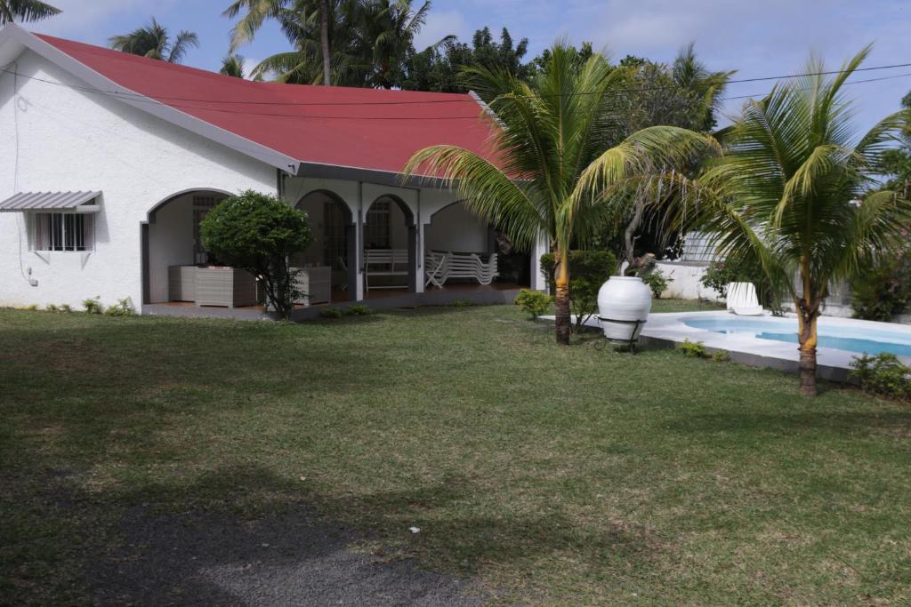 a white house with a red roof and a swimming pool at Le Grand Cacatoie in Blue Bay