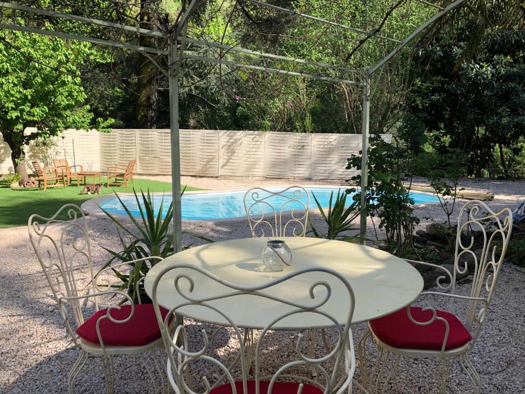 a table and chairs in a yard with a pool at Maison des Ingénieurs in Molières-sur-Cèze