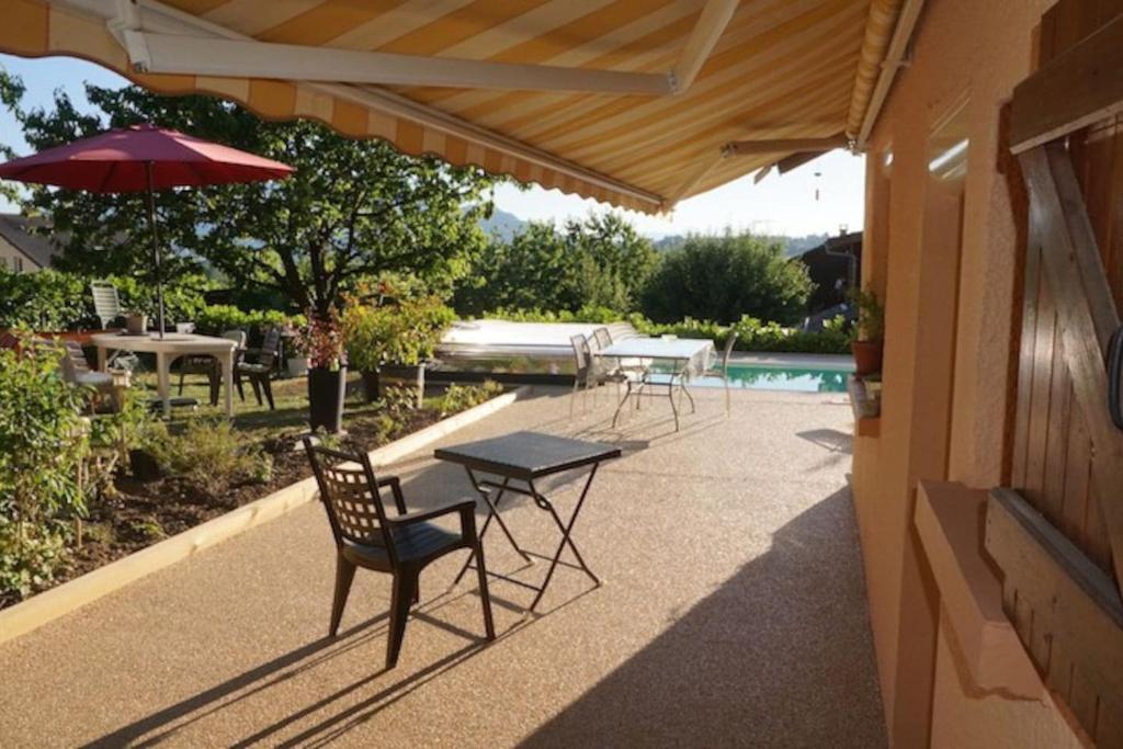 une terrasse avec une table, des chaises et un parasol dans l'établissement LE ROSSIGNOL, à Cranves-Sales