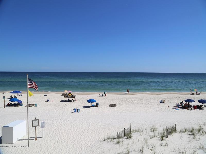 - une plage avec des personnes, un drapeau américain et l'océan dans l'établissement Harbor House B4 Condo, à Gulf Shores