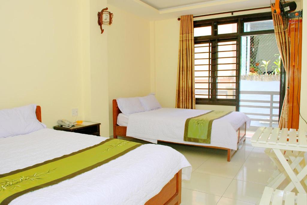 a hotel room with two beds and a window at Champa Hue Hotel in Hue