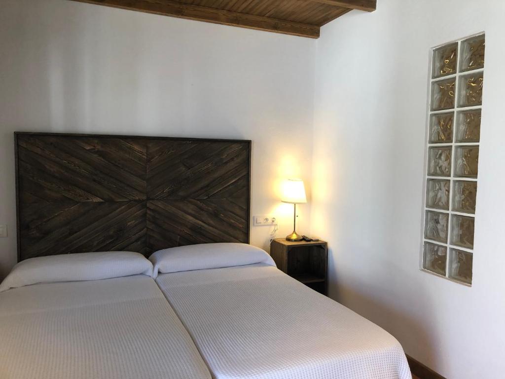 a bedroom with a white bed with a wooden headboard at Alojamiento Rural El Soldao in Medina Sidonia