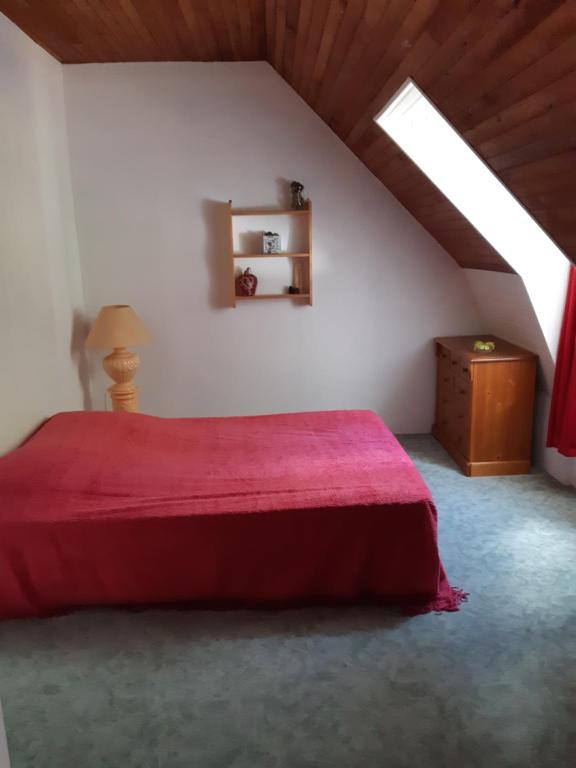 a bedroom with a red bed in a attic at Appartements à la Bourboule in La Bourboule