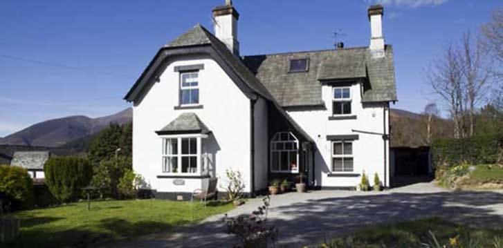 uma grande casa branca com um telhado preto em Claremont House Keswick em Keswick