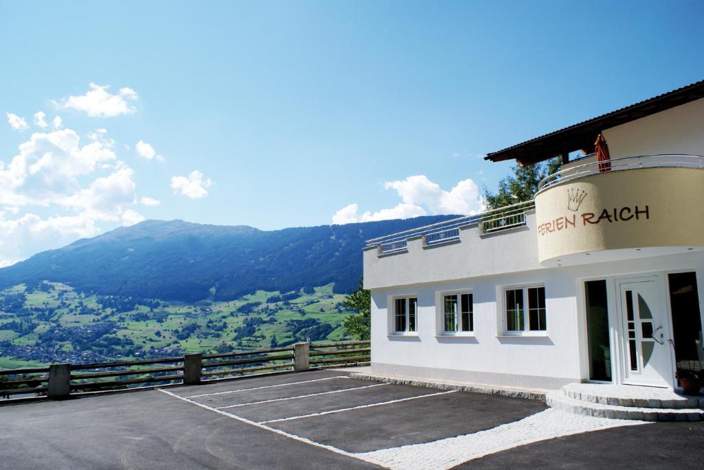 ein Gebäude mit einem Parkplatz vor einem Berg in der Unterkunft Apart Ferienraich in Arzl im Pitztal