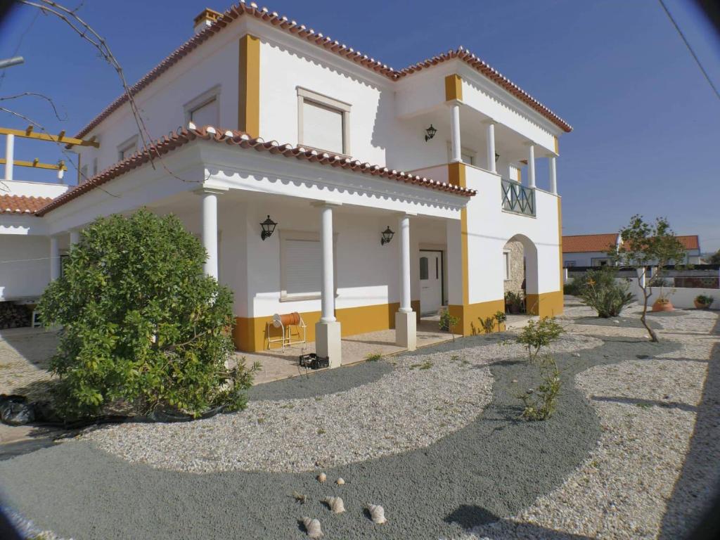 une maison blanche et jaune avec un arbre devant elle dans l'établissement Martin's Villa, à Atouguia da Baleia