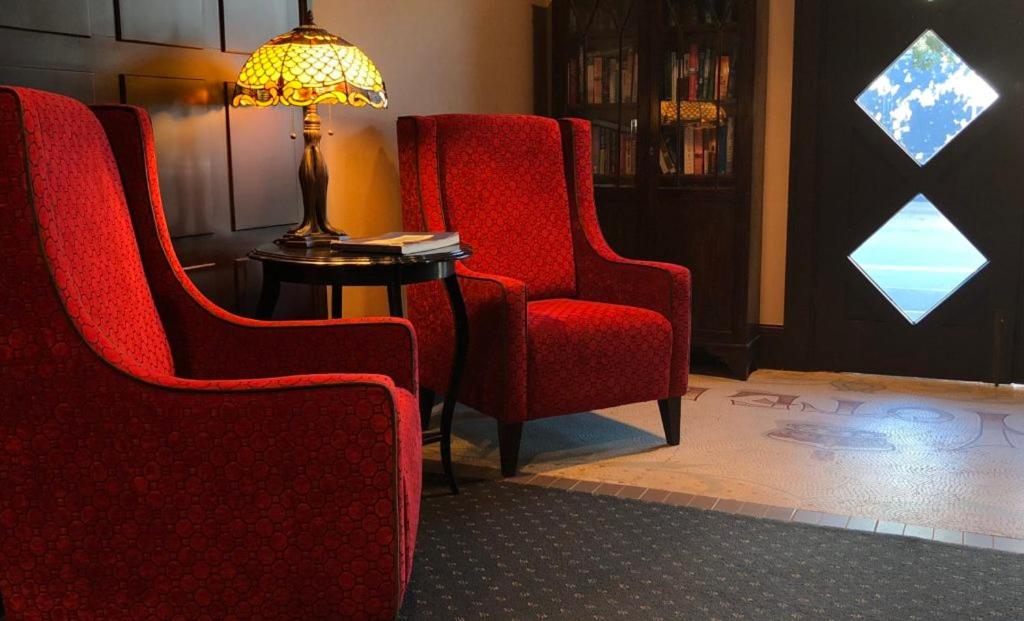 a red chair sitting in a living room next to a lamp at The Crown Hotel in Napier