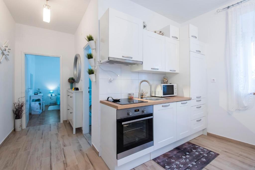 een keuken met witte kasten, een wastafel en een fornuis bij Kaleta apartman in Kali