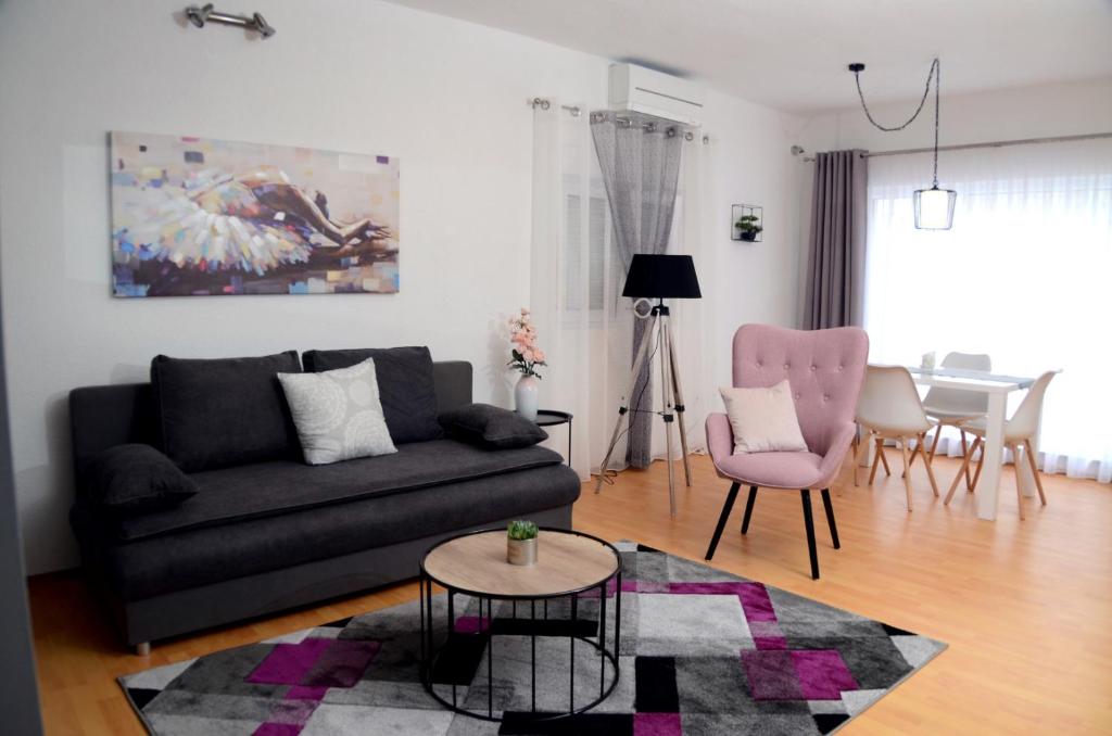 a living room with a black couch and a pink chair at Apartments La Luna in Zadar