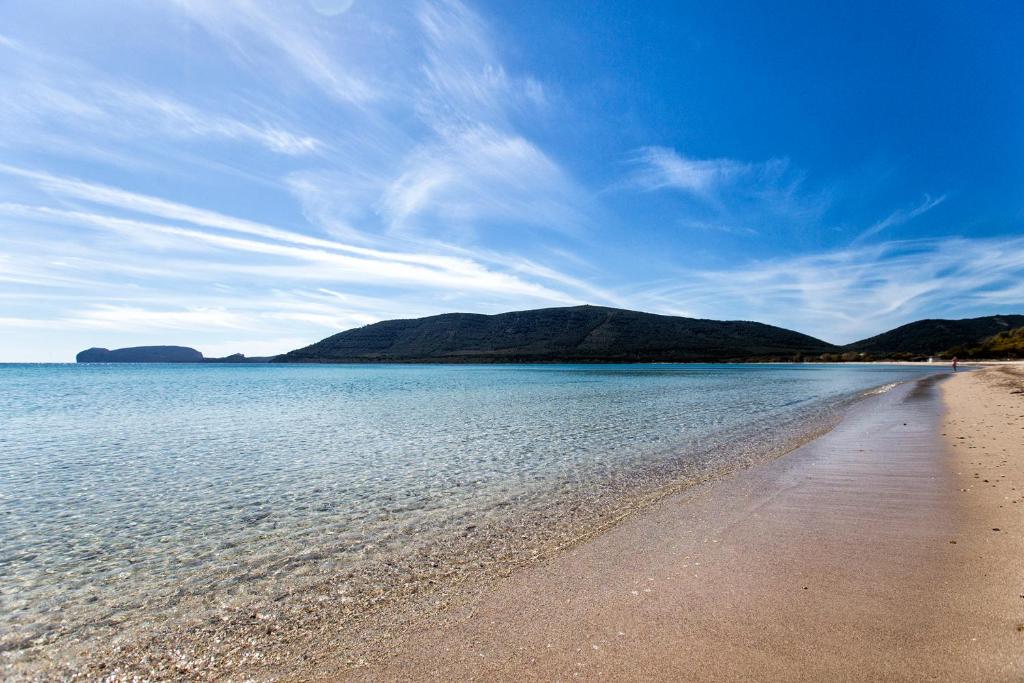 widok na plażę z górami w tle w obiekcie white coral bedrooms self check-in w mieście Alghero