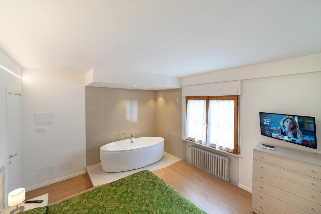 a bathroom with a bath tub and a television in it at Dolomiti Suite in Belluno