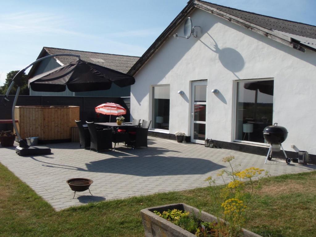 a patio with a table and chairs and an umbrella at Thorupgaard Farm Holiday in Stenum