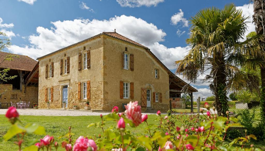 a brick building with a palm tree and flowers at Le Guitou in Monlezun