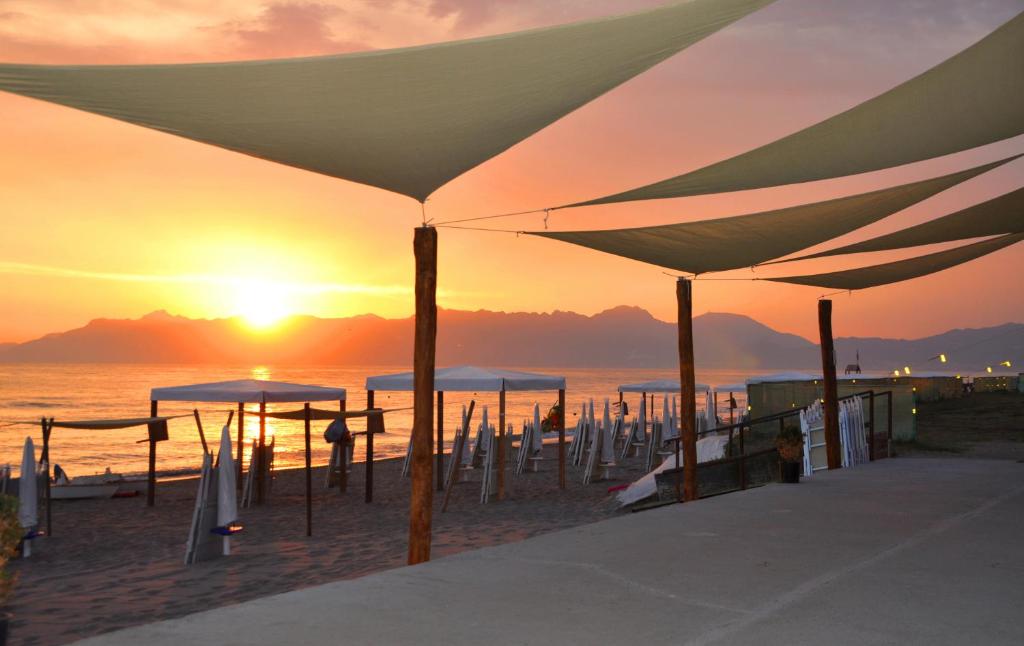 - un groupe de parasols sur la plage au coucher du soleil dans l'établissement Albergo Riviera Spineta, à Battipaglia