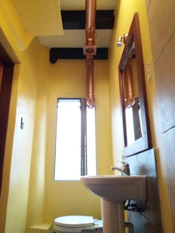 a bathroom with a sink and a toilet and a mirror at Aji Hostel in Santiago