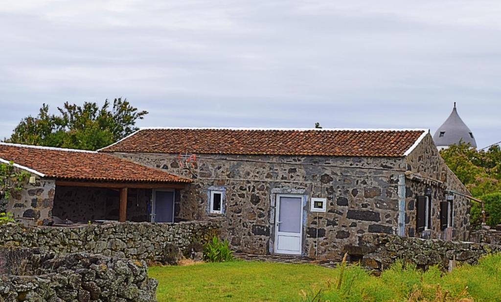 ein altes Steinhaus mit einer Steinmauer in der Unterkunft Casa da Vitória in Santa Cruz da Graciosa