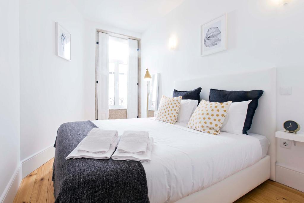 a white bedroom with a large white bed with pillows at Bom Porto Apartments in Porto