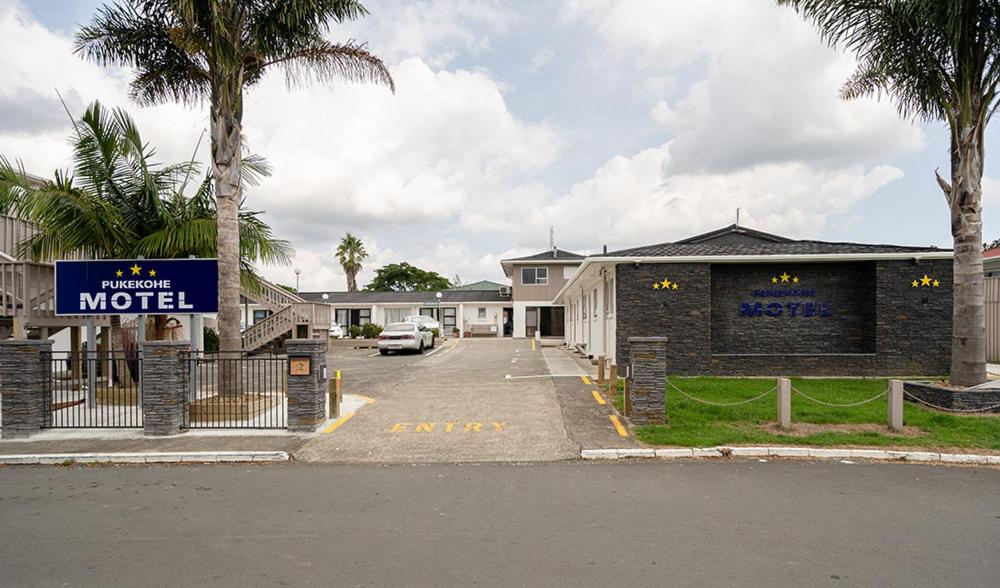 a parking lot with a motel sign in front of a building at Pukekohe Motel in Pukekohe East