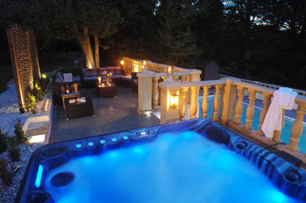 a hot tub in a backyard at night with lights at The New School Rooms - Beautiful, Georgian Apartment with Private Heated Pool and Hot Tub Sleeps 12 with Wifi and Parking near Bath in Box