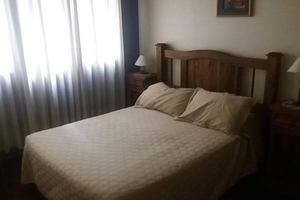 a bedroom with a bed with white sheets and a window at Mendoza Centro 1 dormitorio in Mendoza