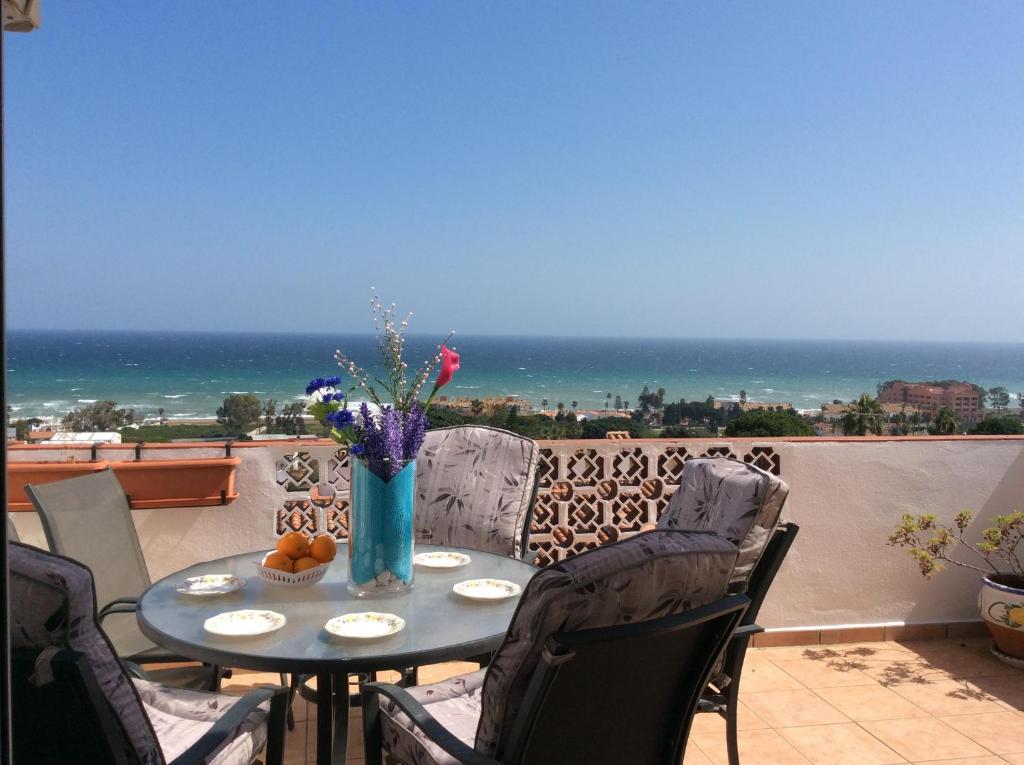 una mesa y sillas en un balcón con vistas al océano en DUQUESA BY THES SEA - HACIENDA GUADALOUPE, en Manilva