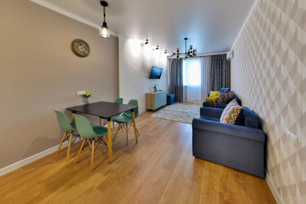 een woonkamer met een bank en een tafel en stoelen bij Apartment Lazurnyi Kvartal in Astana