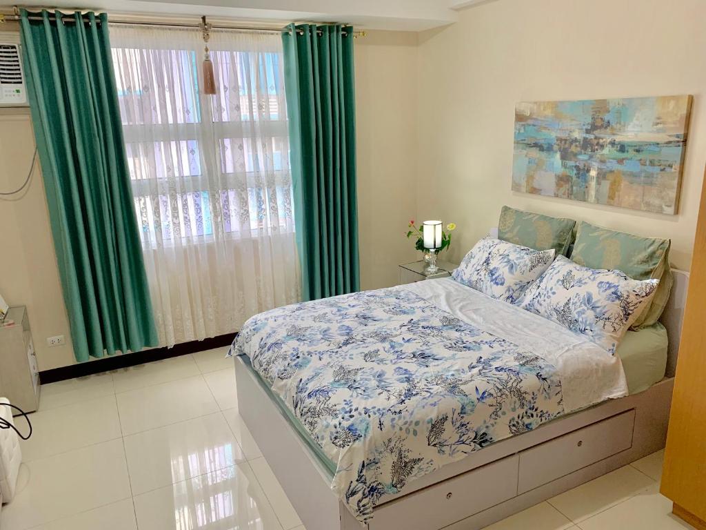 - une chambre avec un lit et une fenêtre avec des rideaux verts dans l'établissement Chillax Studio 101 Newport Boulevard, à Manille