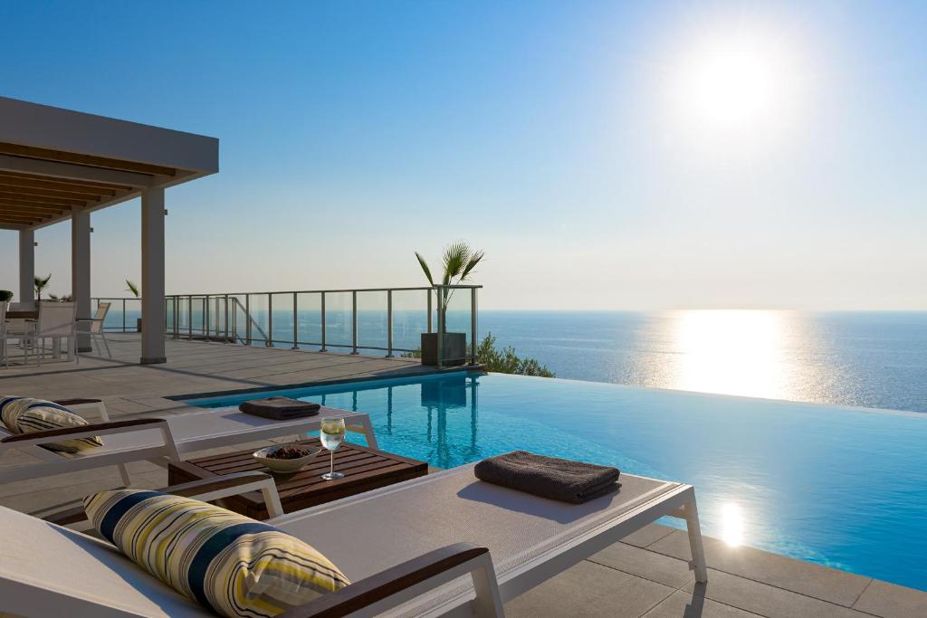 una piscina con mesas y sillas junto al océano en Kathisma Bay Villas - Luxury Villas- Villa Oceanos, en Kalamitsi