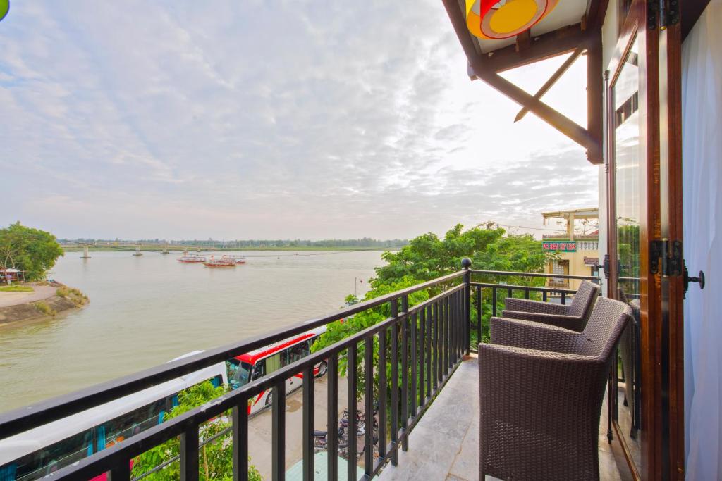 a balcony with two chairs and a view of the river at Hoa Vang Riverside Villa in Hoi An
