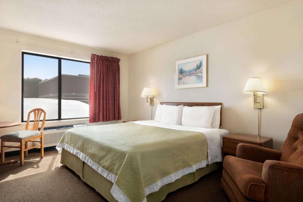 a hotel room with a bed and a large window at Days Inn by Wyndham Eagle River in Eagle River