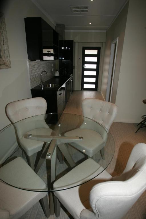 a glass table and white chairs in a kitchen at Kindred Lodge Apartments in Leeton