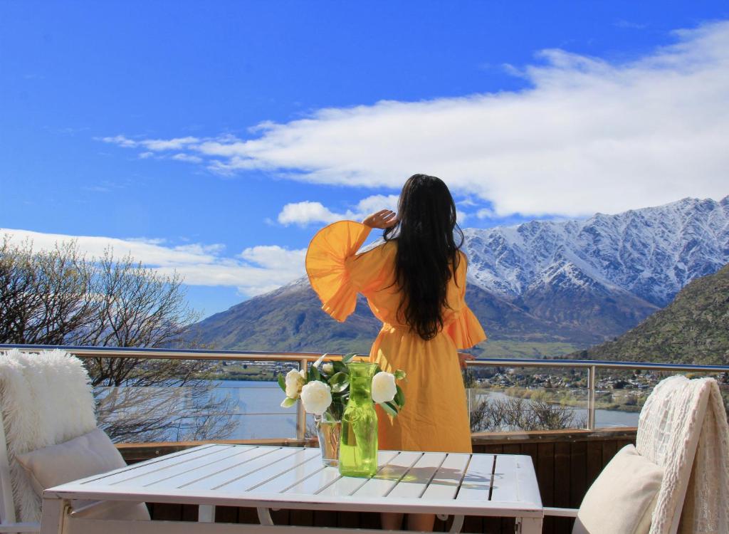 a woman in a yellow dress holding an umbrella on a balcony at Breakfast at Tiffanys in Queenstown