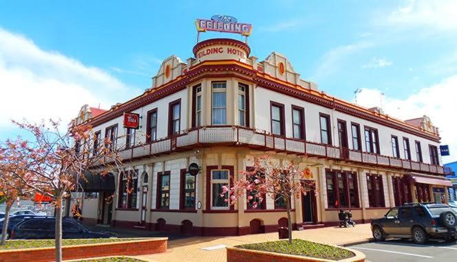 Feilding Hotel في فيلدينغ: مبنى على شارع فيه سيارات تقف امامه