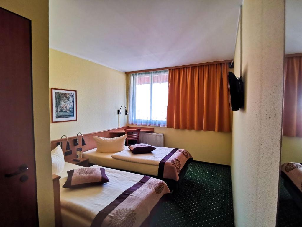 クヴェードリンブルクにあるAcron-Hotel Quedlinburgのベッド2台と窓が備わるホテルルームです。