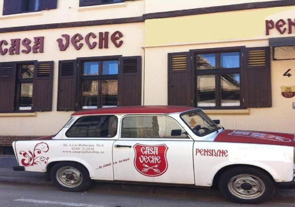 un coche blanco y rojo estacionado frente a un edificio en Casa Veche, en Sibiu